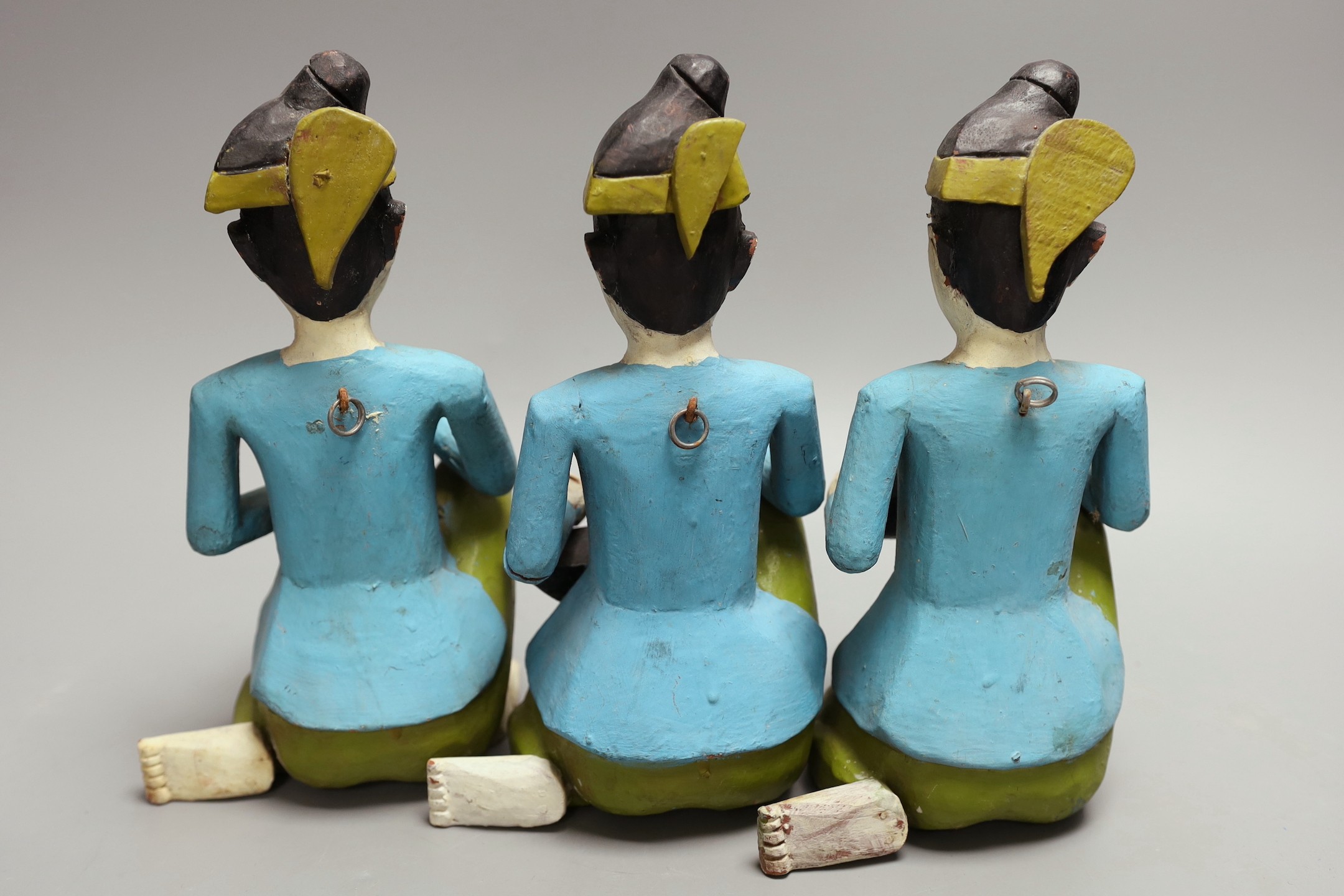 Three Malaysian painted wooden musican figures, 24cm tall